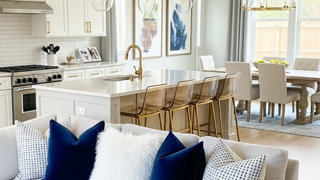 A modern living, kitchen, and dining combo with a large island and a sofa with bold blue cushions