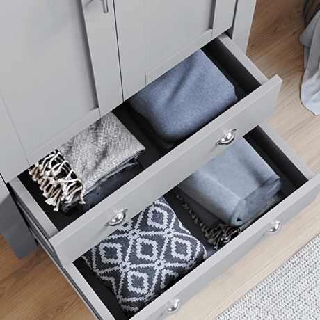 Close-up of grey 2 door wardrobe with drawers, part of a bedroom set, showing open drawers neatly filled with folded blankets and throws.