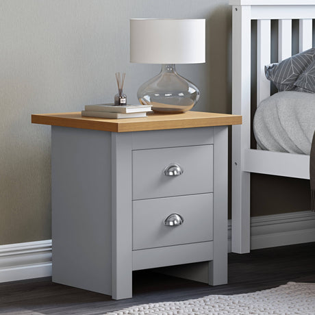 2 drawer bedside table with a top surface holding books and a lamp, perfect for a modern bedroom.