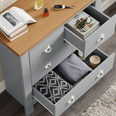 Open drawer view of grey shaker chest showing neatly folded clothes and accessories, highlighting drawer depth and use.