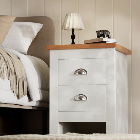 White 2 drawer bedside table from Shaker 4 Piece Bedroom Set with oak-effect top and silver handles, styled beside a bed with lamp and decor.