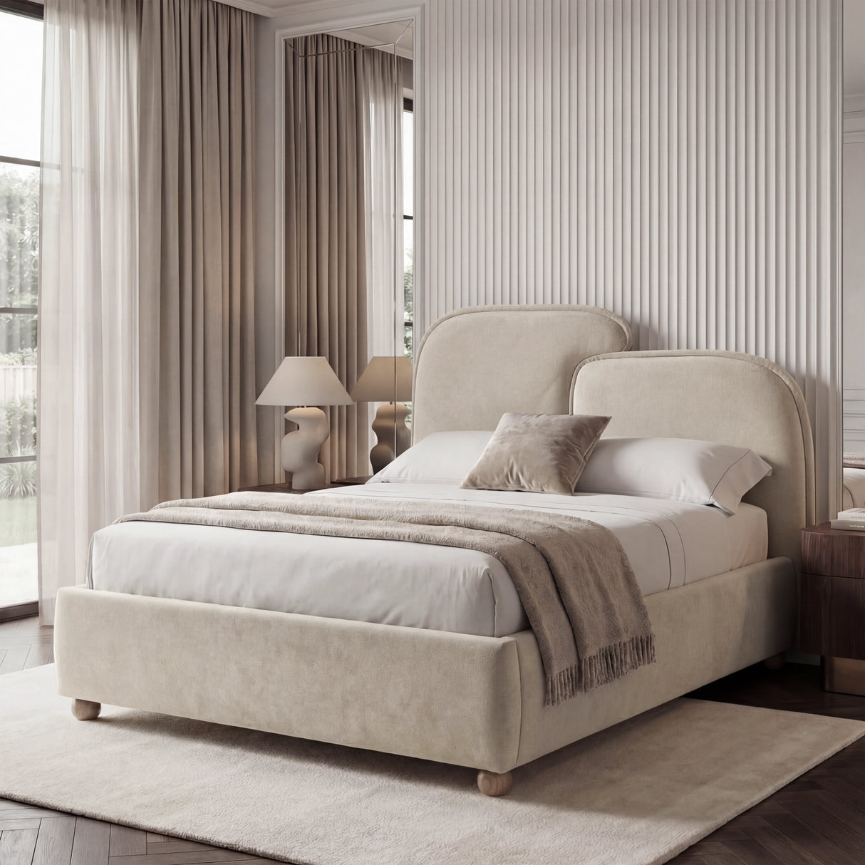 Biege king size bed frame placed near a window, with soft fabric surfaces and layered bedding