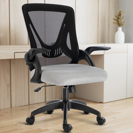 The black and grey mesh chair sits comfortably in a home office, with a working desk in the backdrop.