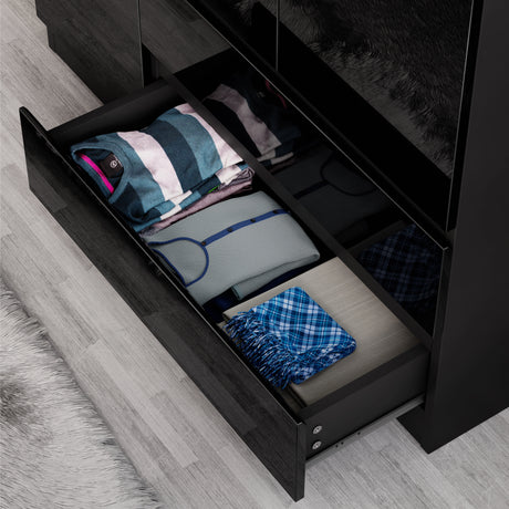 Open drawer of black high gloss wardrobe displaying folded garments, emphasizing its deep storage and smooth drawer action.
