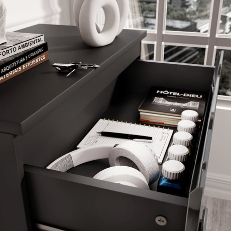 Close-up of drawer in black high gloss bedside table from the bedroom set, storing headphones, books, and accessories.