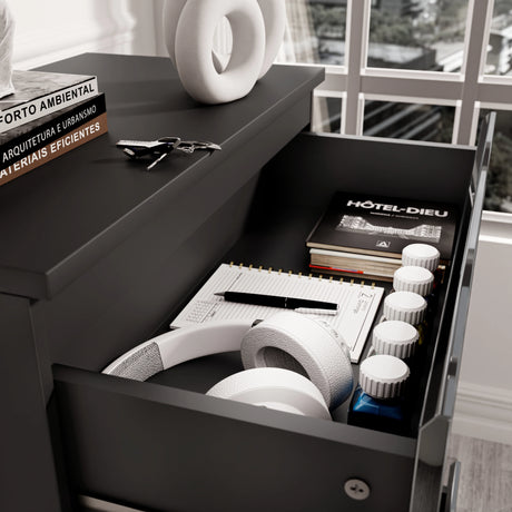 Close-up of drawer in black high gloss chest, showing storage for headphones, notebooks, and daily essentials.