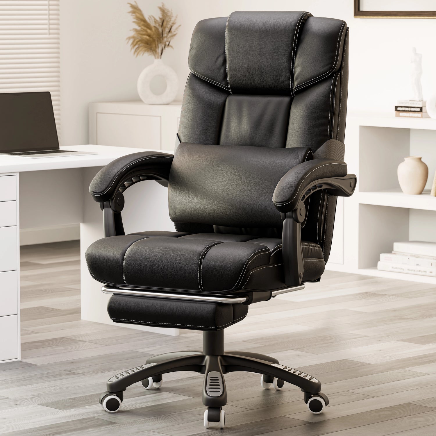 black leather office chair with footrest and lumbar pillow placed beside a wooden desk in home office