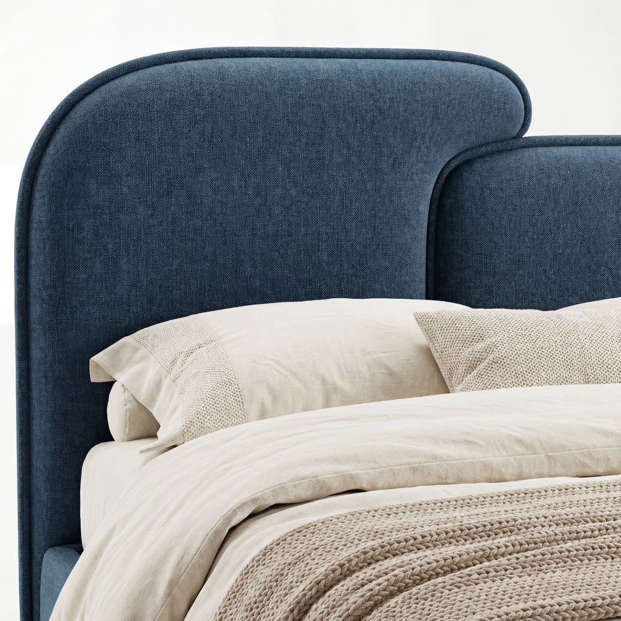 Rounded upholstered headboard in blue fabric, showing stitched contours and soft cushioning of a king bed
