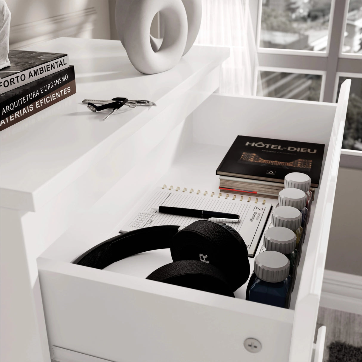 Top drawer of white High Gloss Chester Drawers with headphones, notebooks, and paint bottles, highlighting versatile storage use.