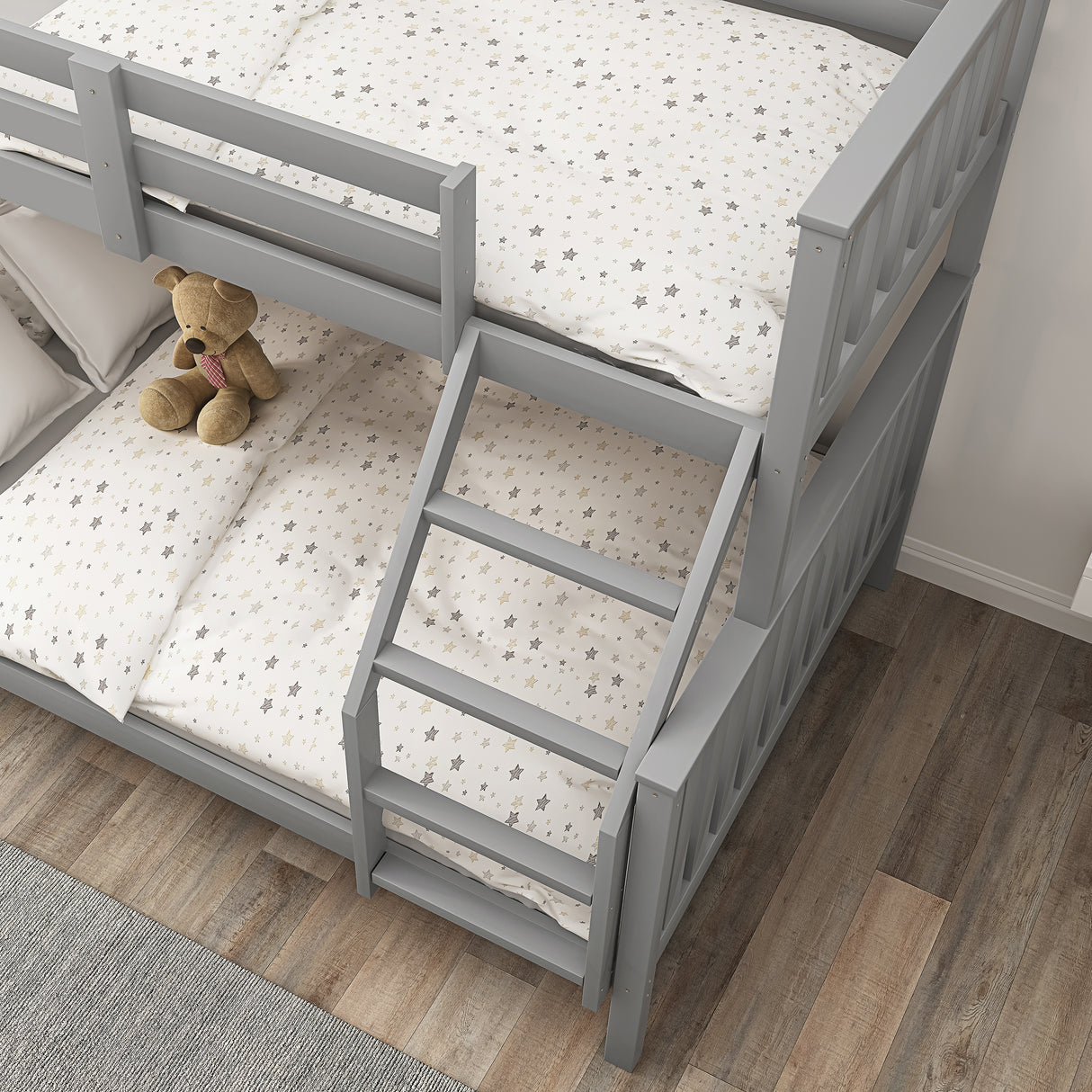 Top-down view of grey triple bunk bed with star-patterned bedding, showing ladder placement and space-saving design.