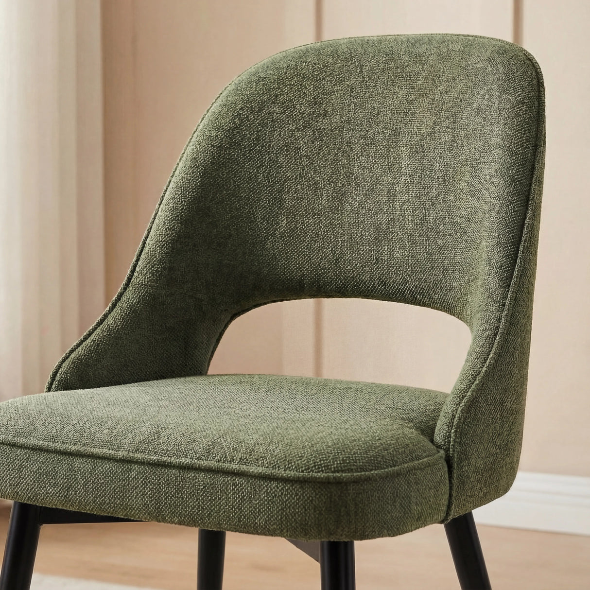Close-up shot of a green Aldridge dining chair's textured fabric, highlighting its modern curve design and comfort.