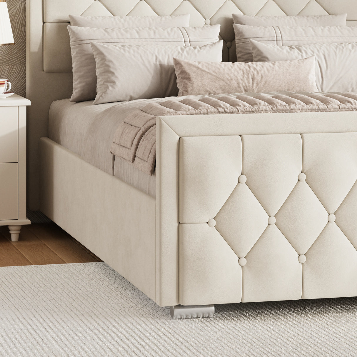 Beige velvet ottoman bed with a cross-puffed footboard placed near a white nightstand in a bedroom.