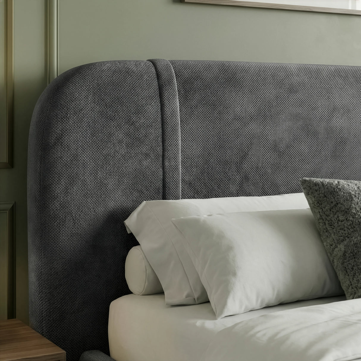 Close detail of textured dark grey headboard fabric with curved upper edge and cushions placed in a room