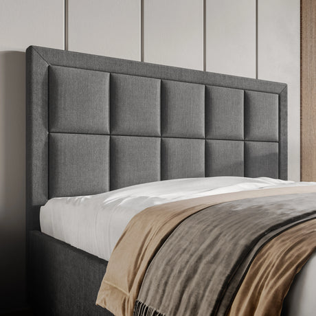 Gray upholstered headboard with a bed and beige blanket in a bedroom setting.
