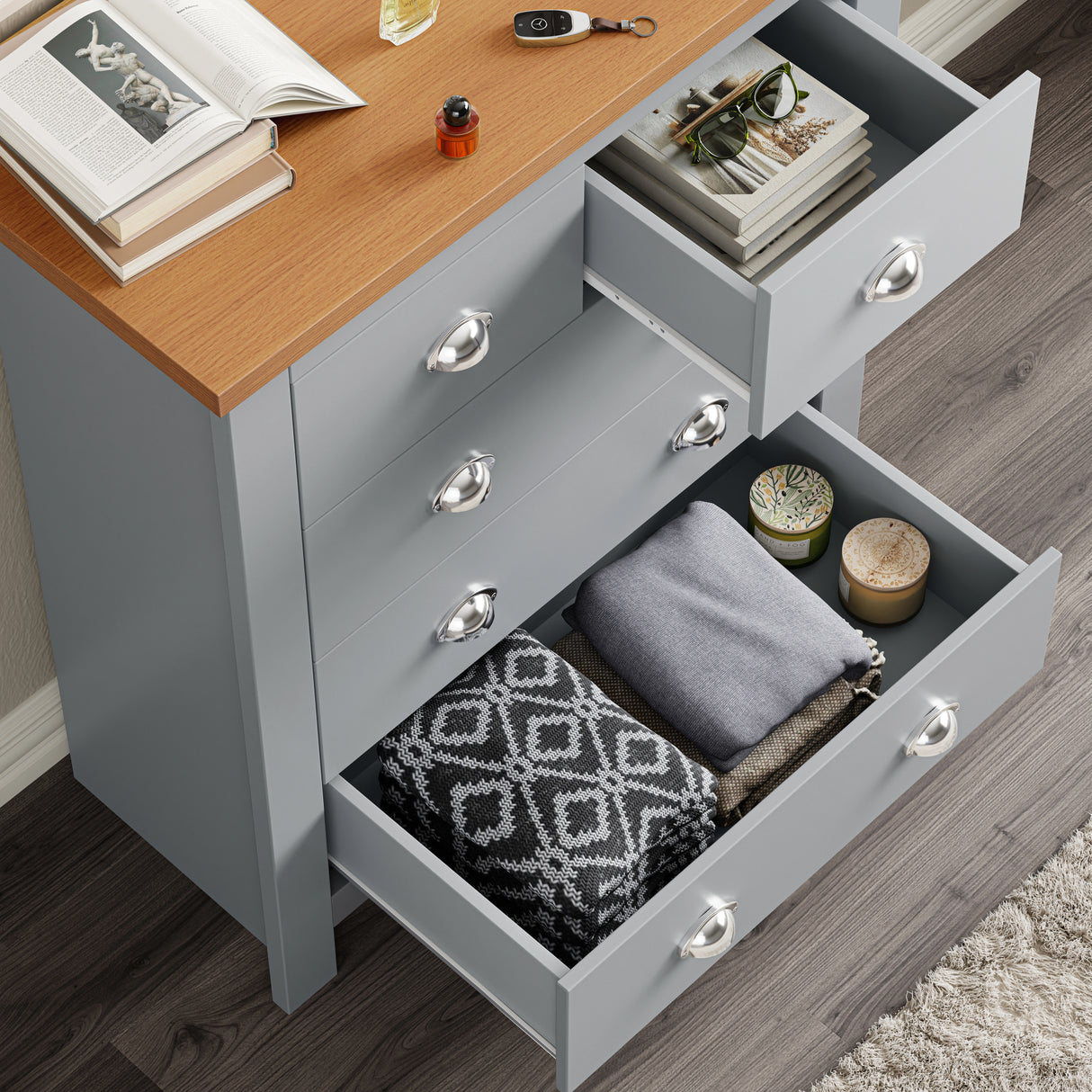 Open drawer view of grey shaker chest showing neatly folded clothes and accessories, highlighting drawer depth and use.