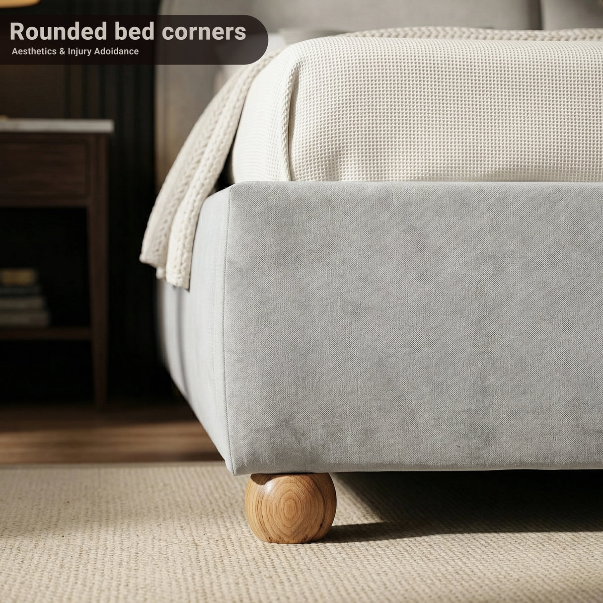 Lower front corner of a grey fabric double bed frame with rounded edges and small wooden support legs