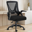 In a home office setup, the black mesh chair is positioned with a working desk in the backdrop for ergonomic seating.