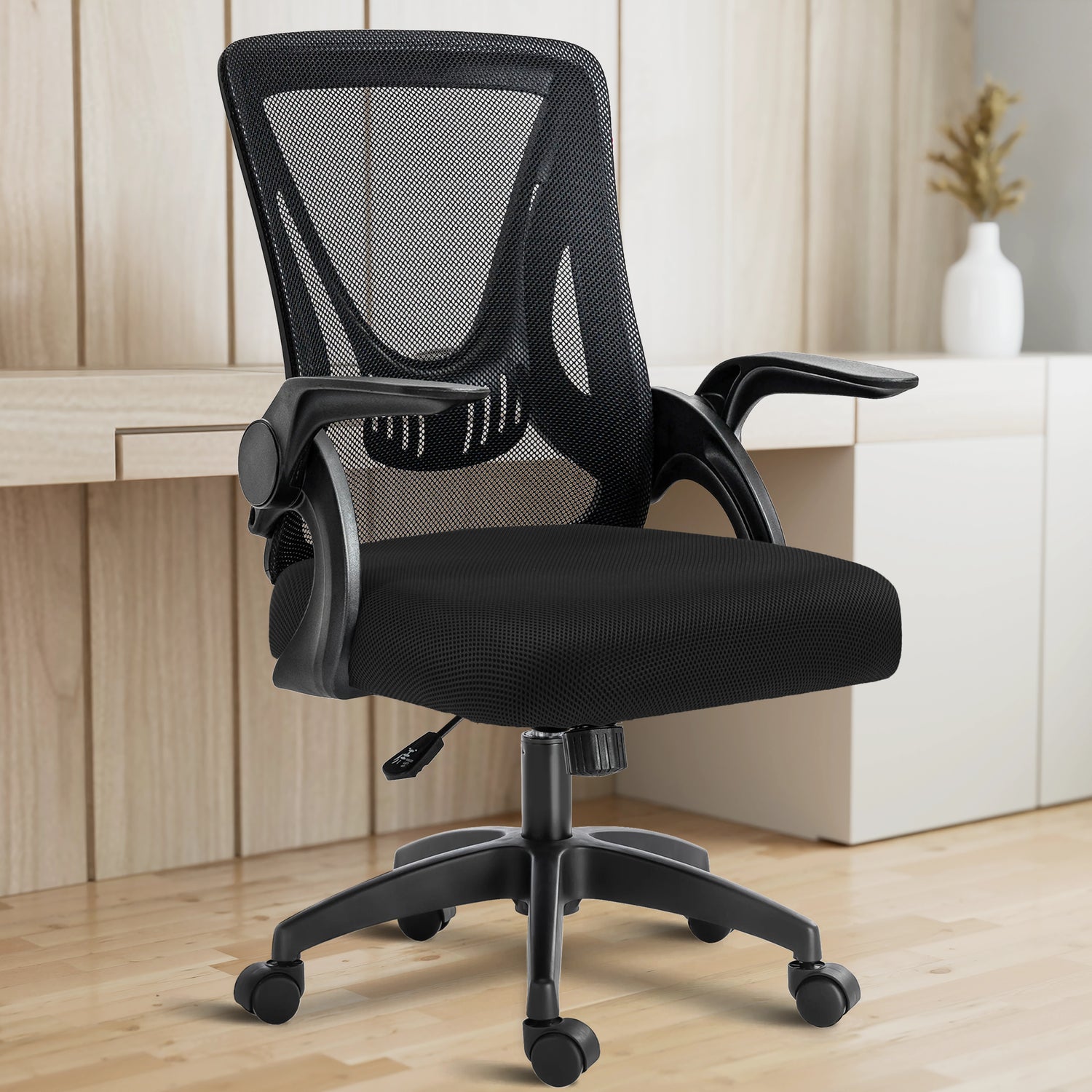 In a home office setup, the black mesh chair is positioned with a working desk in the backdrop for ergonomic seating.