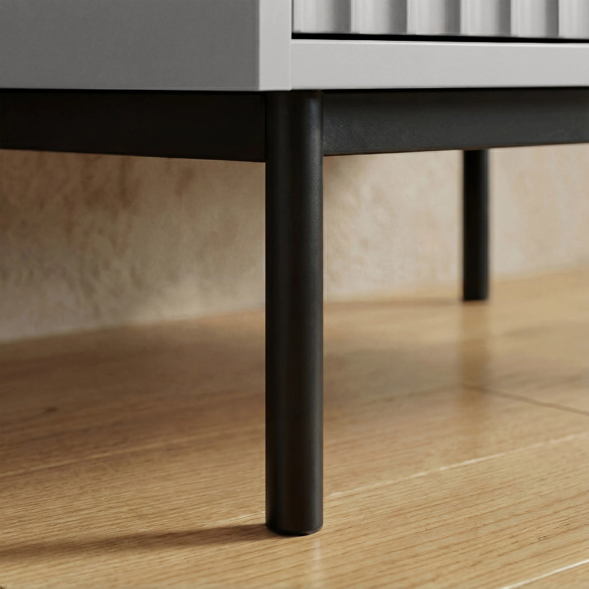 Grey flutrina wardrobe raised black metal leg detail supporting cabinet structure placed on a wooden flooring