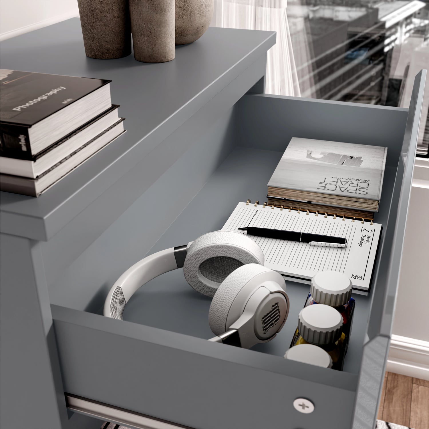 Top drawer of grey High Gloss Chester Drawers with books, headphones, and stationery, showcasing practical storage use.
