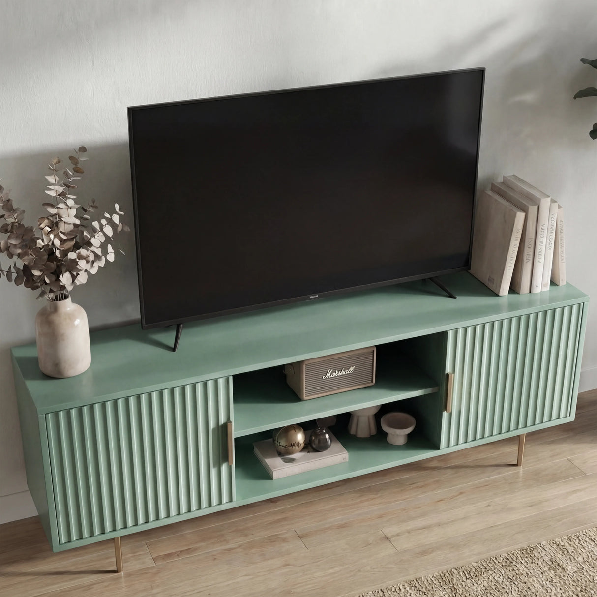 Green TV media unit with vertical textured panels and silver legs, styled for a modern living room centerpiece.
