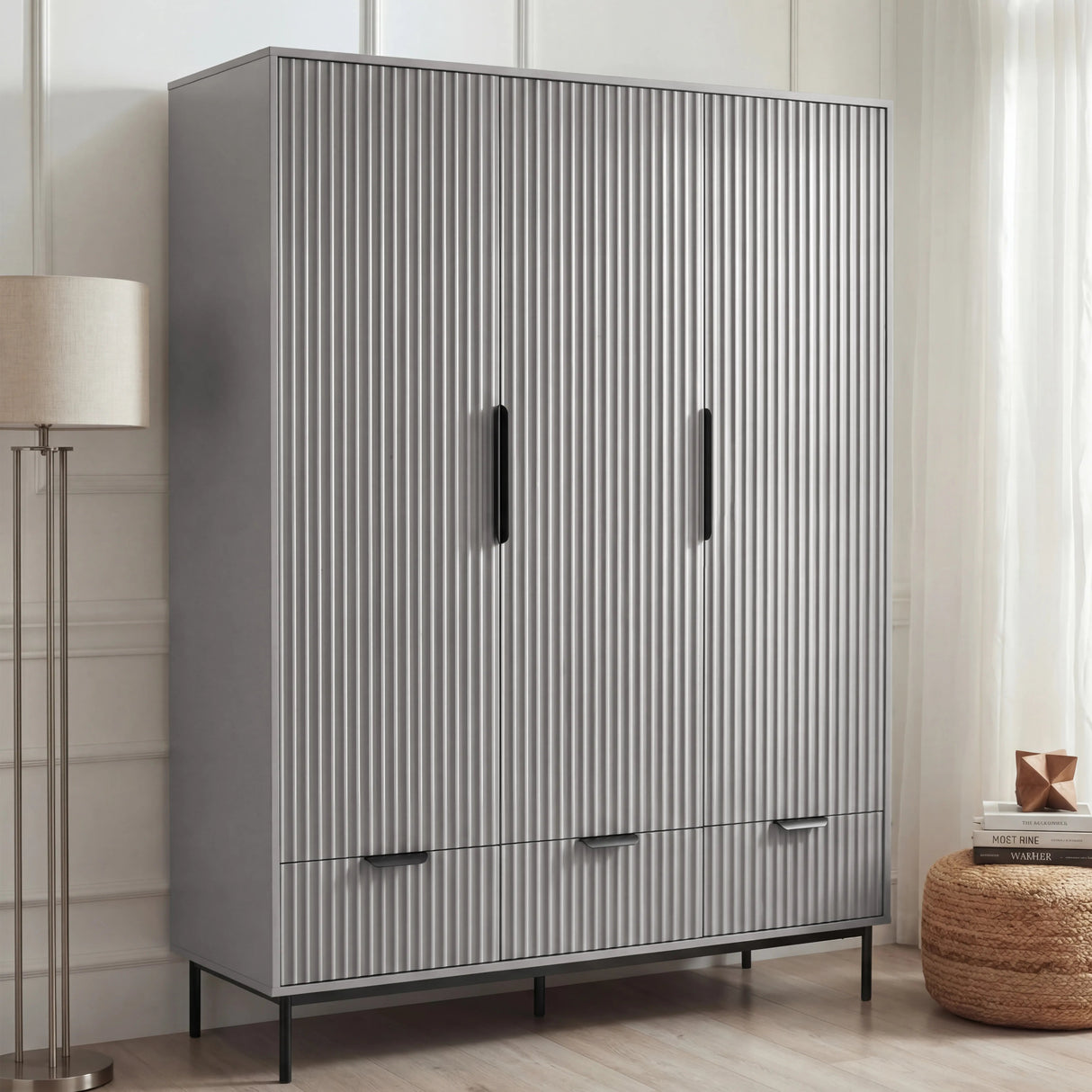 Grey three door wardrobe with drawers styled in modern room with neutral walls and decor