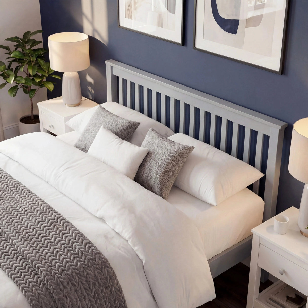 Wooden grey bed frame with a headboard having a slatted pattern, with layered pillows and bedside furniture in bedroom