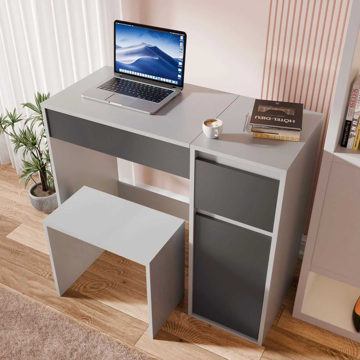 Gray desk with a laptop, books, and a cup on a wooden floor.
