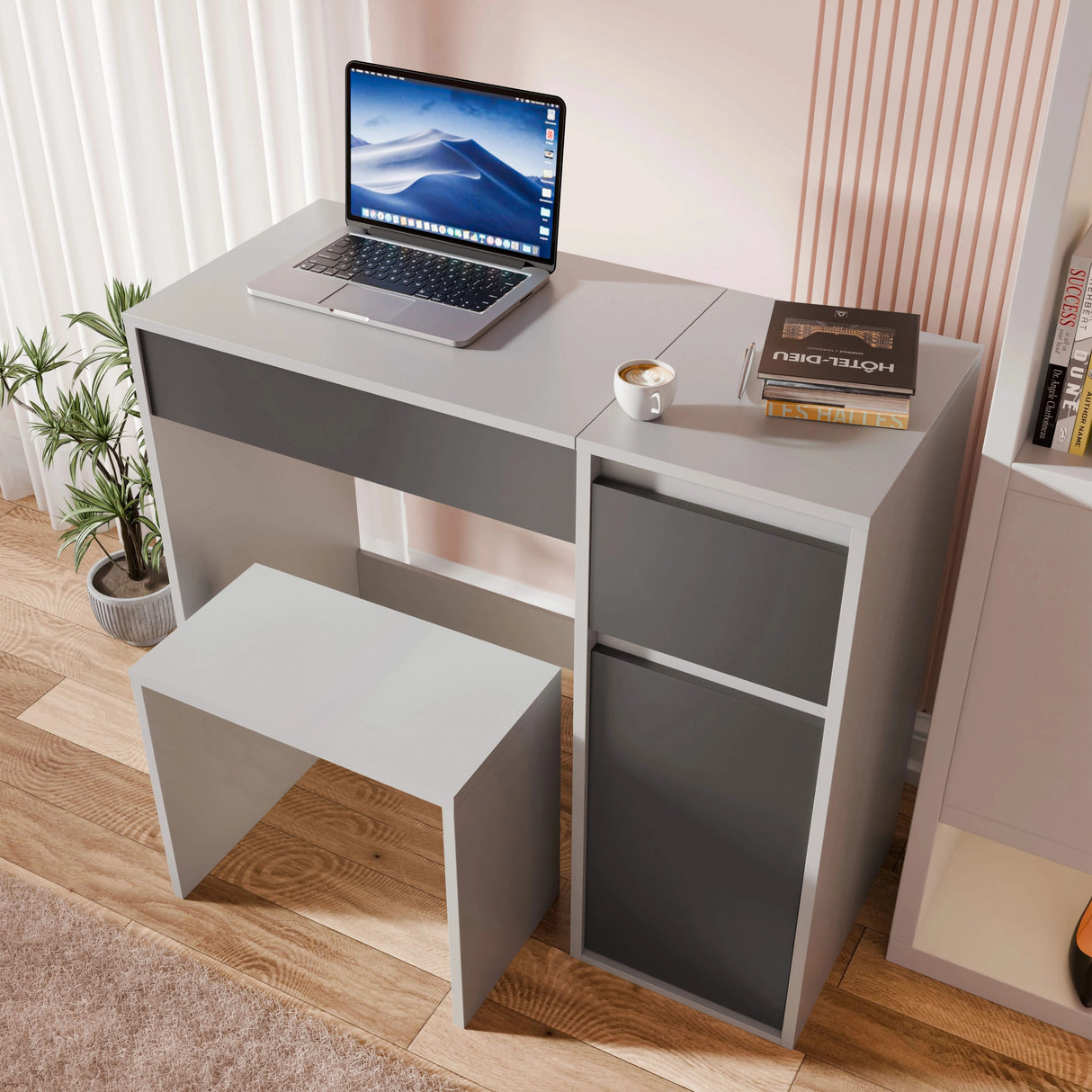 Gray desk with a laptop, books, and a cup on a wooden floor.
