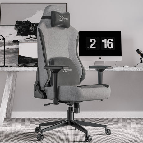 Xstriker Ergonomic Fabric Reclining Gaming Chair with 4D Armrest for Adults in grey, placed in a modern home office setup with a desktop computer and accessories.