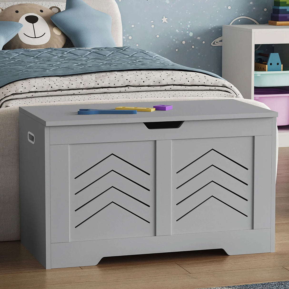 Children's room with a gray storage bench, teddy bear, and colorful toys.