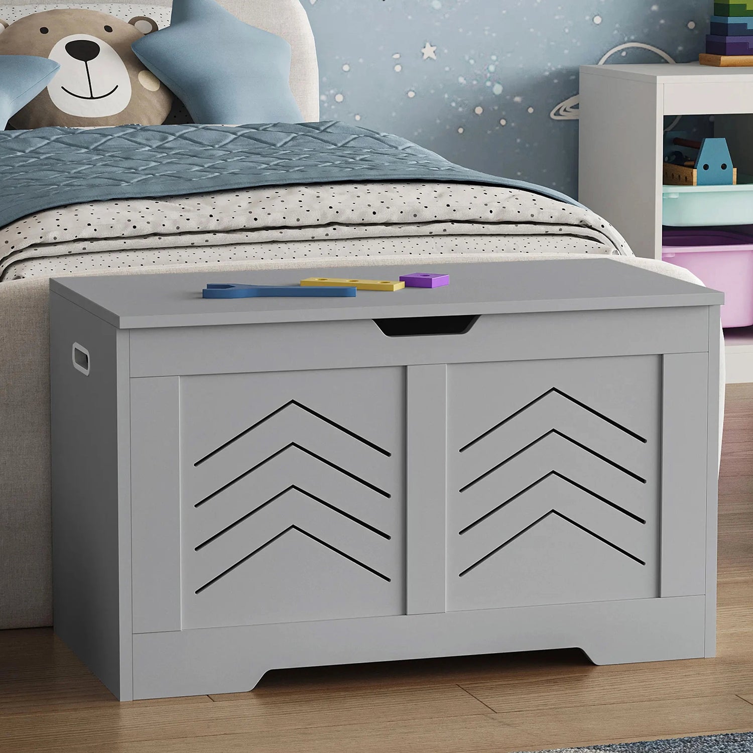 Children's room with a gray storage bench, teddy bear, and colorful toys.