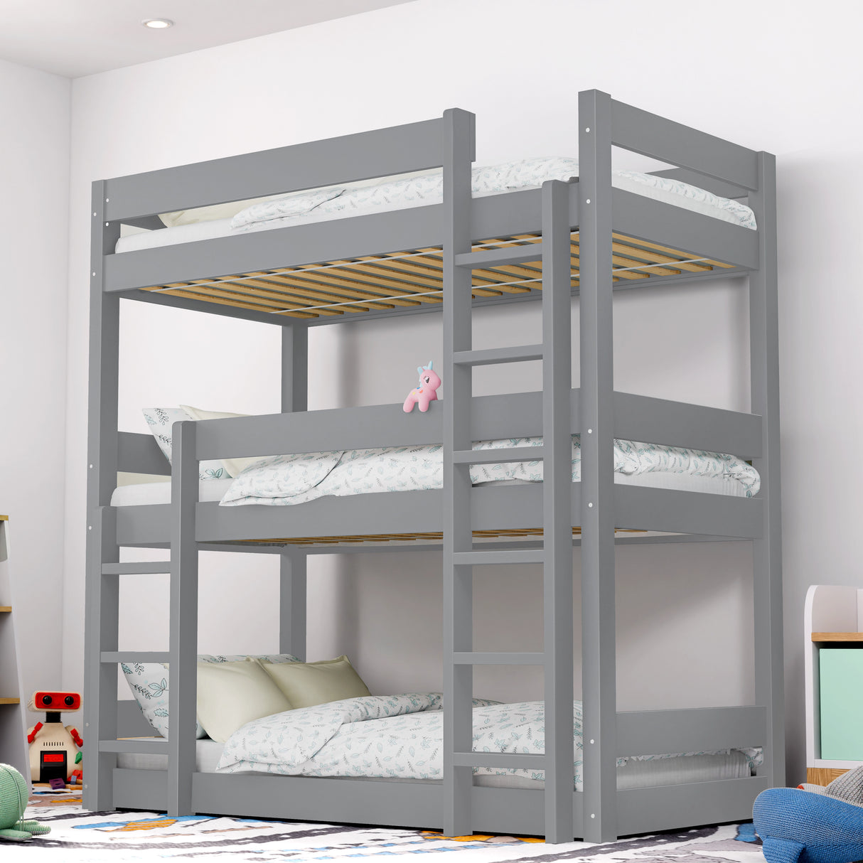 full view of a grey triple bunk bed with white bedding in a children's bedroom decorated with toys