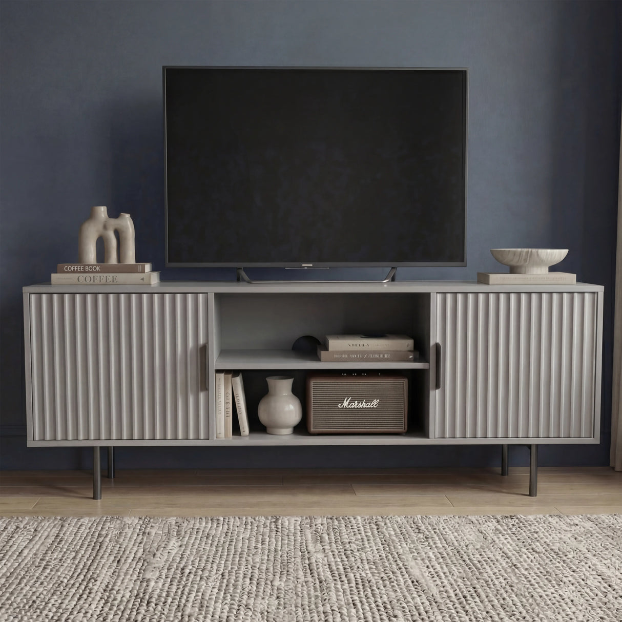 Modern grey TV entertainment unit with vertical fluted doors and silver legs for a contemporary living room aesthetic.