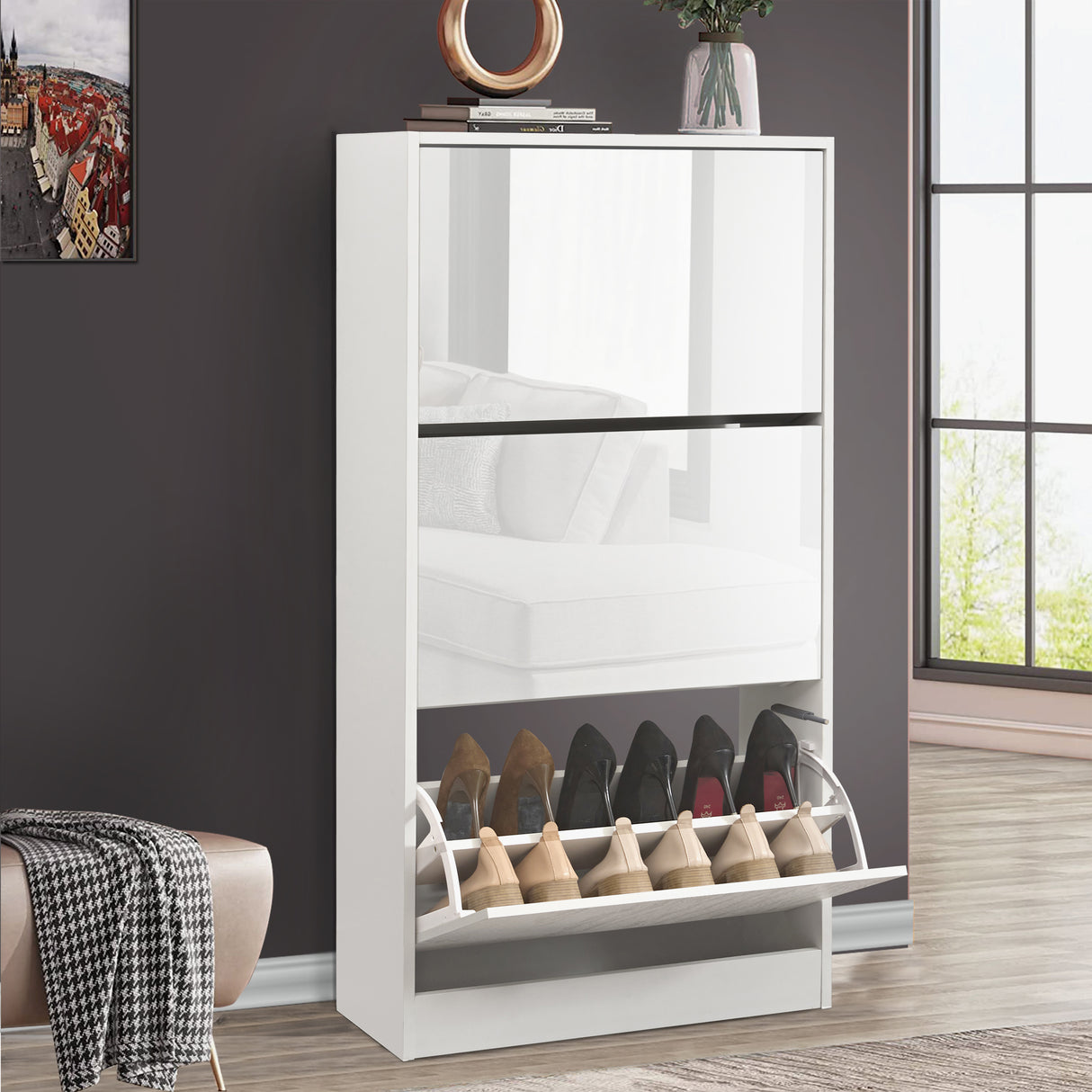 White gloss shoe cabinet with three pull down drawers and soft reflective surface capturing the living room furniture.
