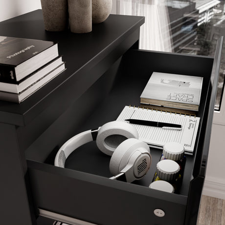 High Gloss Tall Chest of Drawers with open top drawer showing white headphones, notebooks, and small containers. Sleek black 5 drawer chest for bedroom storage.