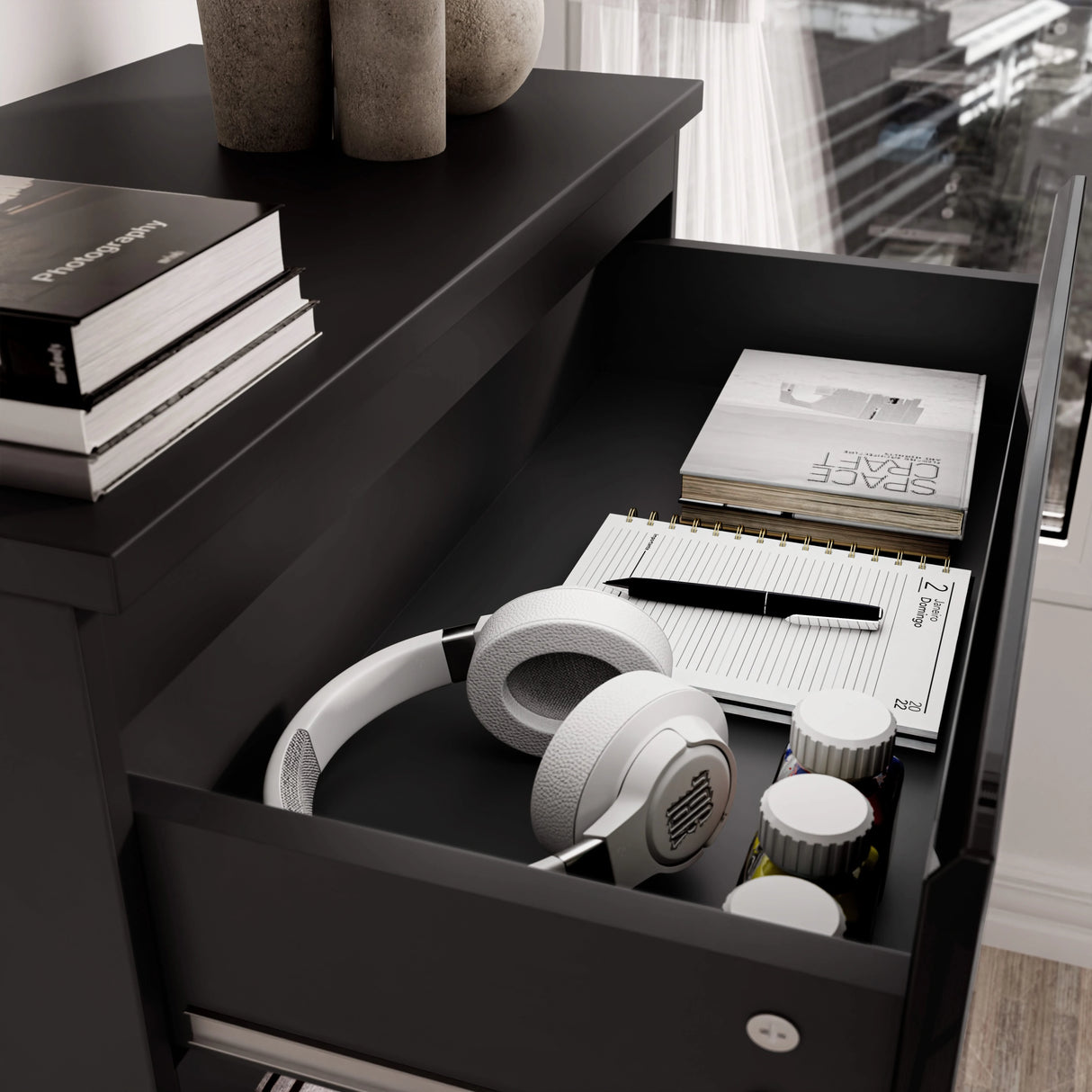 High Gloss Tall Chest of Drawers with open top drawer showing white headphones, notebooks, and small containers. Sleek black 5 drawer chest for bedroom storage.