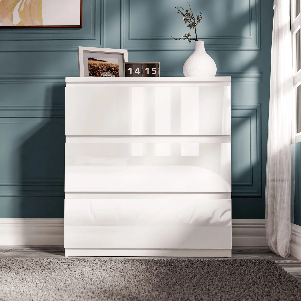 High Gloss 3 Drawer Chest of Drawers in white with handleless design, placed in a modern bedroom with blue panel walls and decor.
