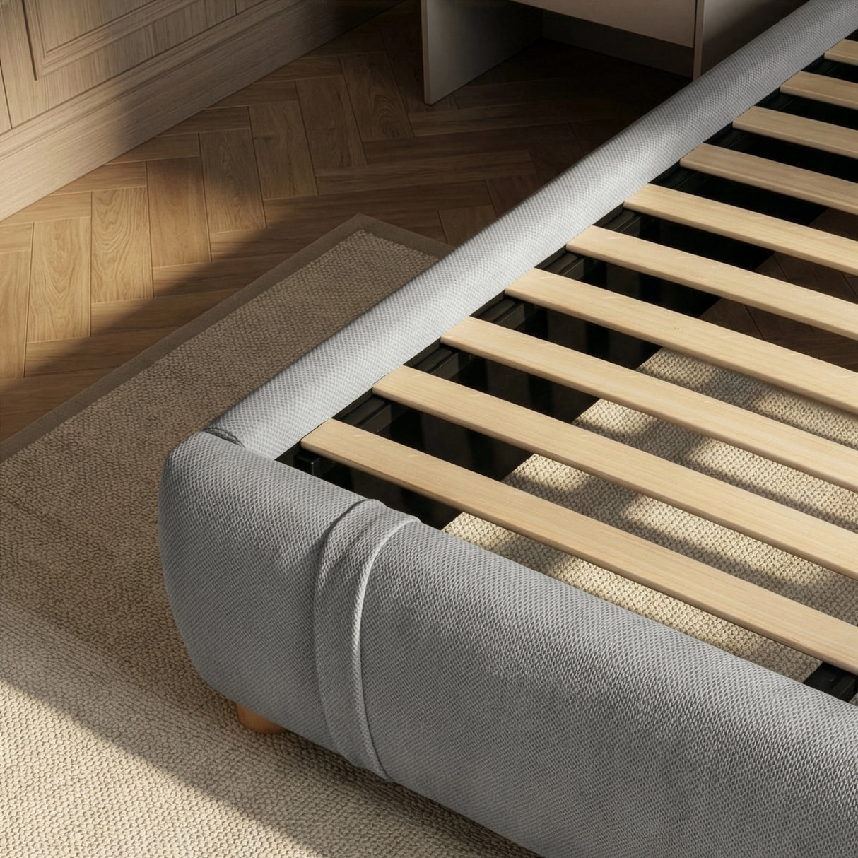 Interior wood support system with evenly spaced slats inside an upholstered king grey bed frame