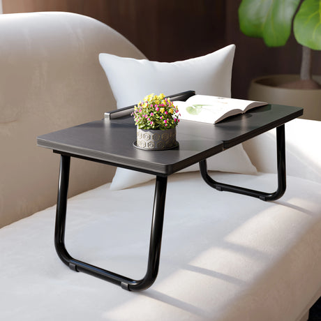 Portable folding laptop desk with height adjustable black legs and built-in cup holder, placed on a sofa for home office or bed use.