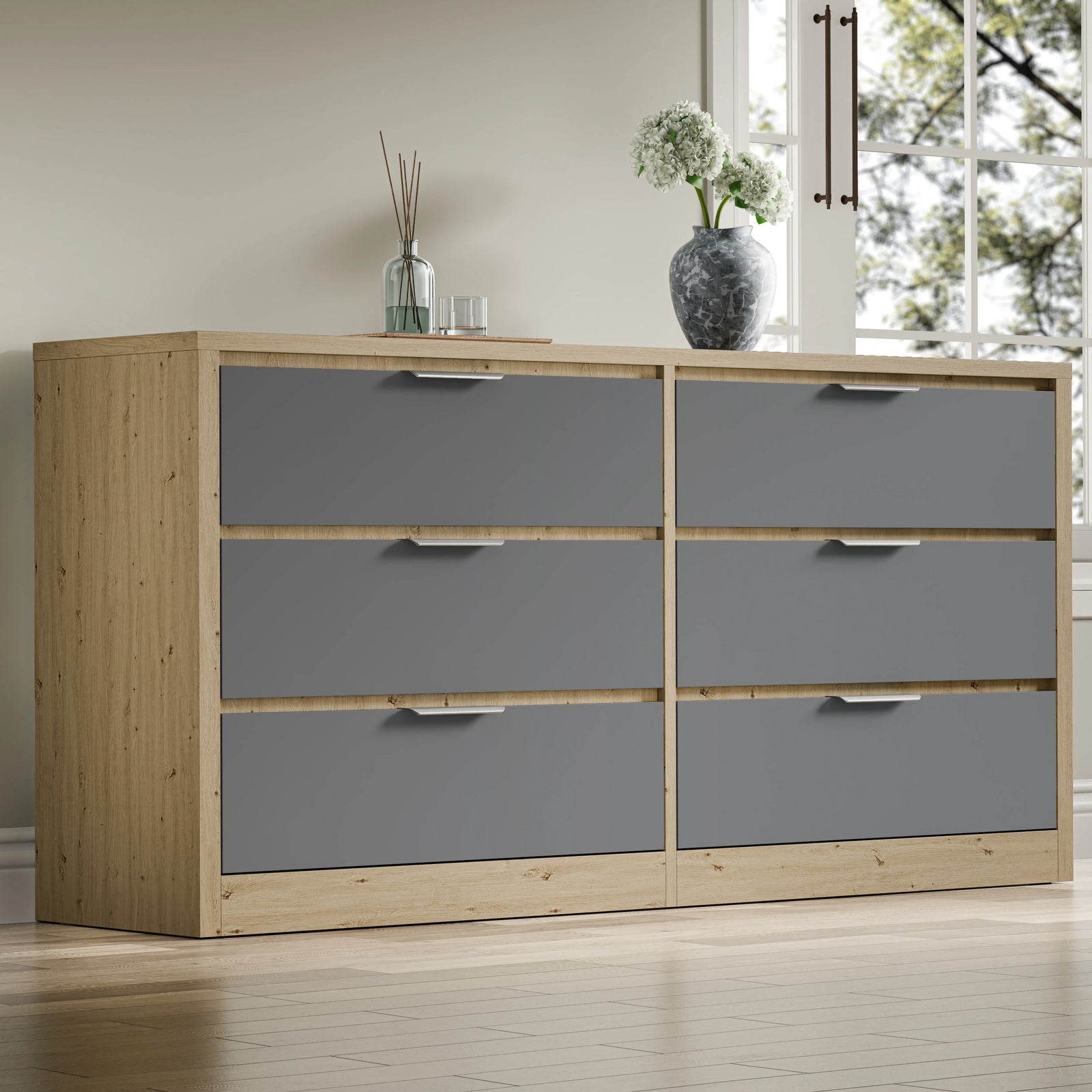 Large chest of drawers in a two-tone oak grey finish, showing six drawers, placed in a room near a window