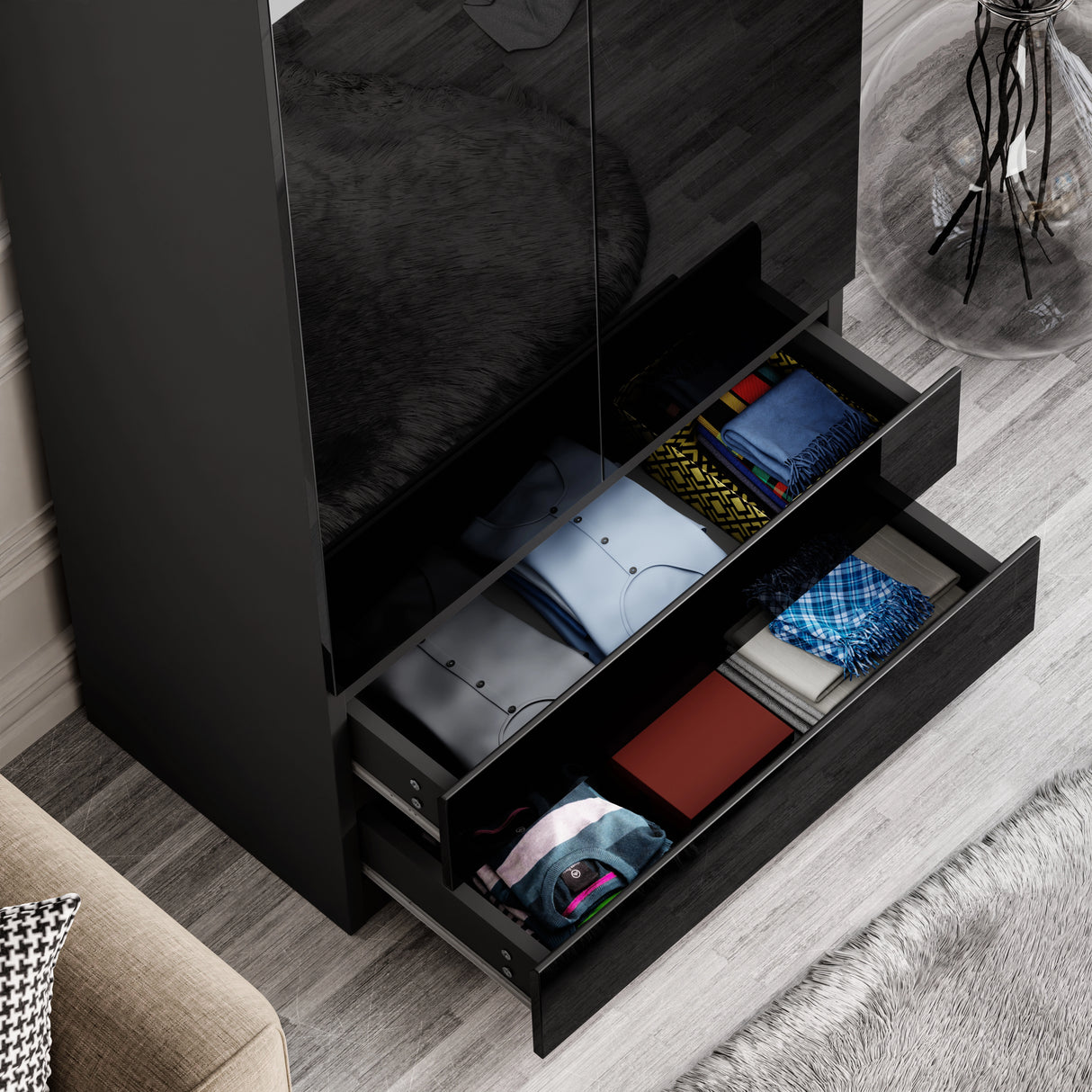two bottom drawers of black high gloss wardrobe pulled out showcasing folded clothes in vibrant colours