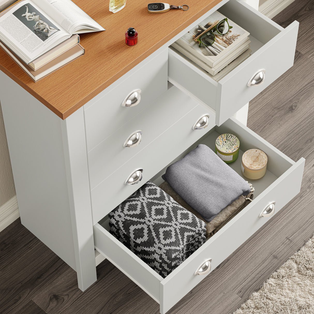 Top-down view of white shaker chest with open drawers displaying folded clothes and decor, showcasing storage capacity.