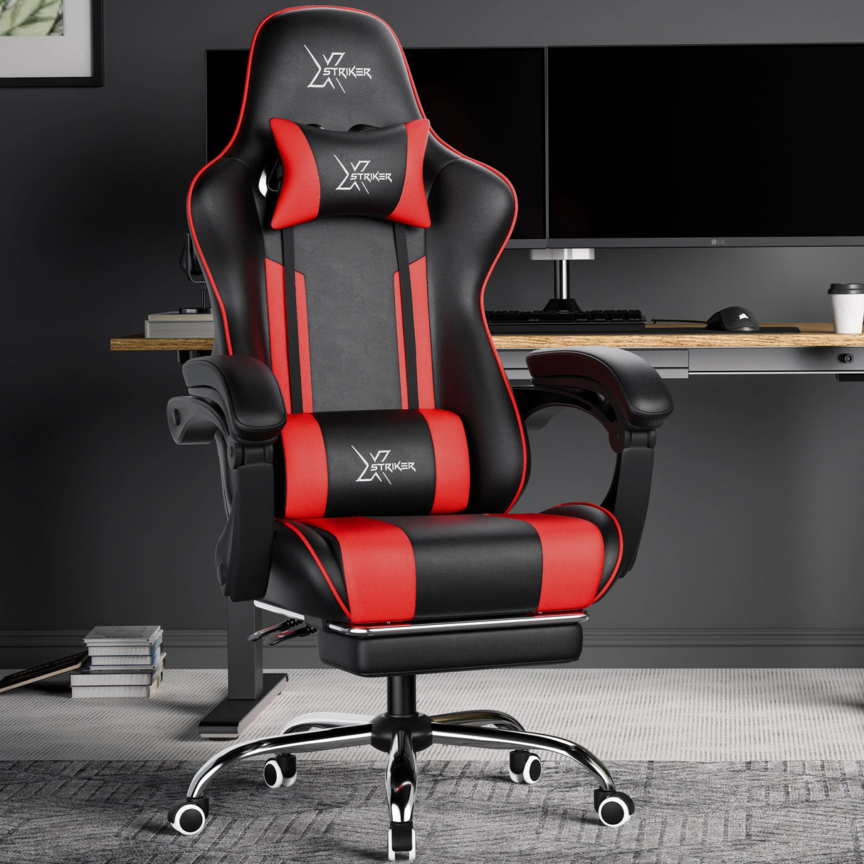 Xstriker Gaming Chair With Footrest in black and red, placed in a modern home office setup with dual monitors and an adjustable desk.