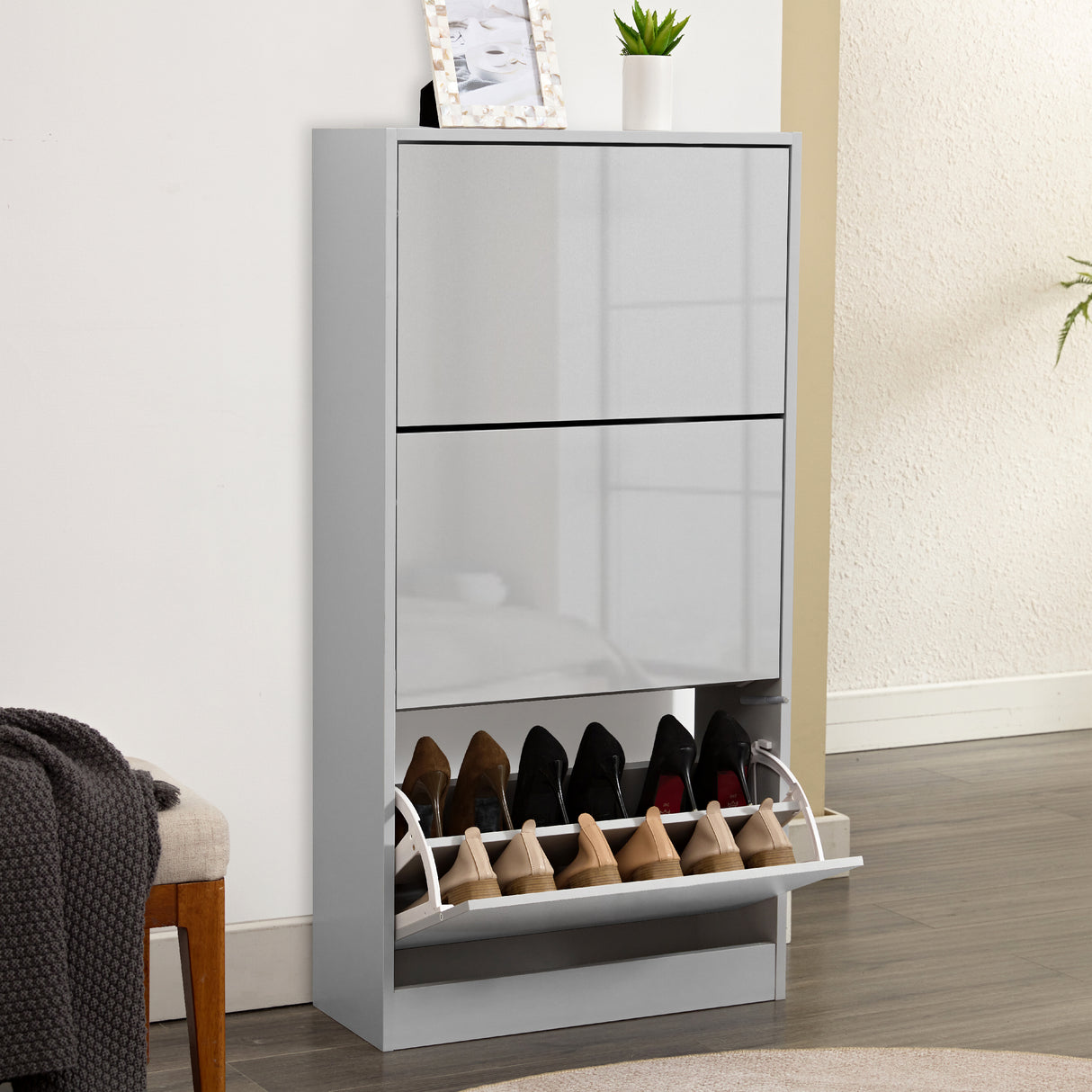 Sleek grey gloss shoe cabinet in 3 tier shoe cabinet style, front panel softly reflecting living room furniture.