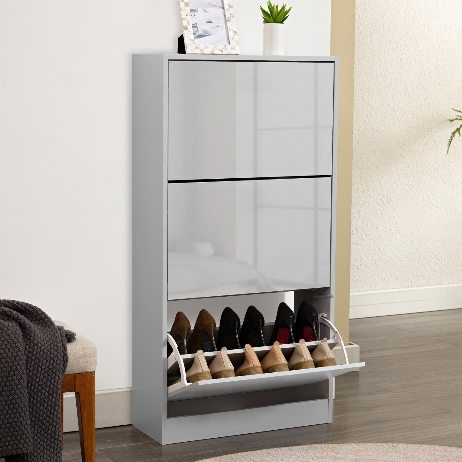 Sleek grey gloss shoe cabinet in 3 tier shoe cabinet style, front panel softly reflecting living room furniture.
