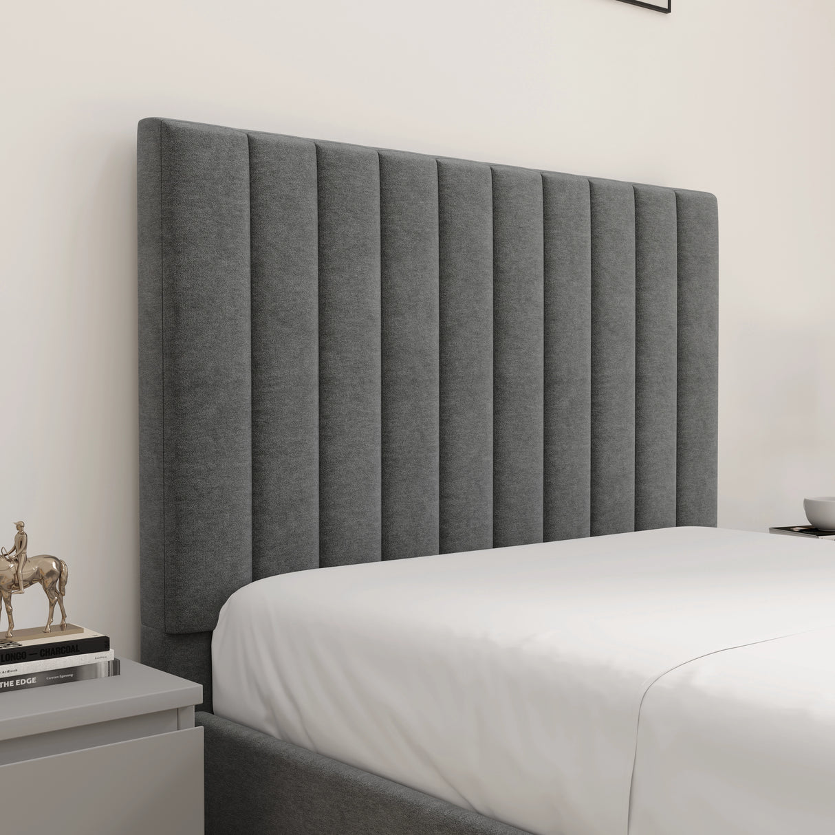 Gray upholstered headboard in a bedroom setting with a white bedspread.