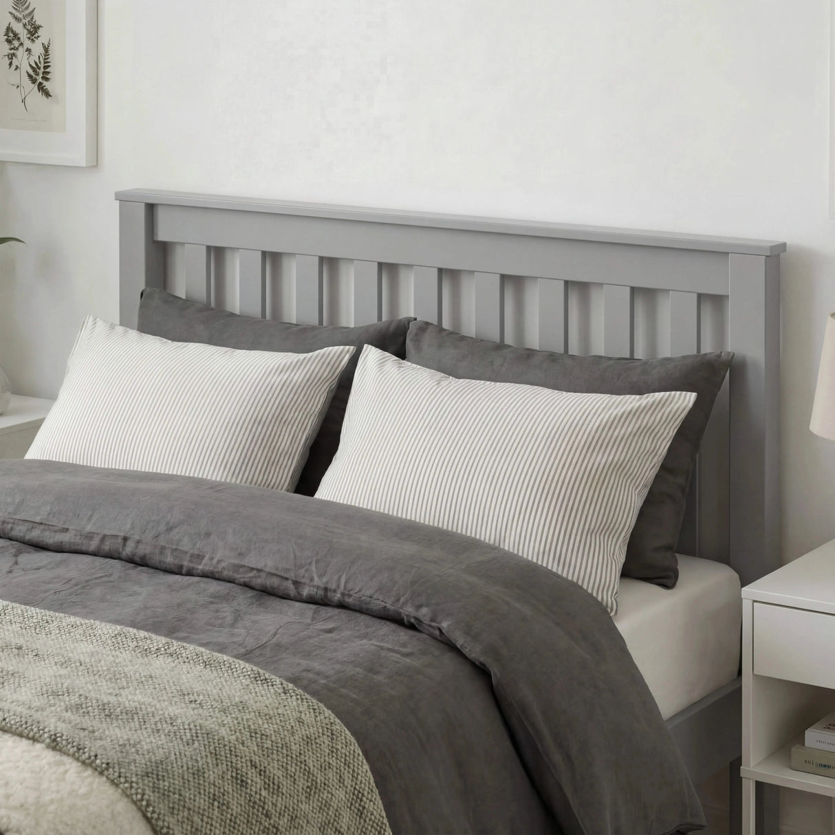 Grey wooden single bed frame with slatted headboard, soft bedding, and a minimalist bedroom design
