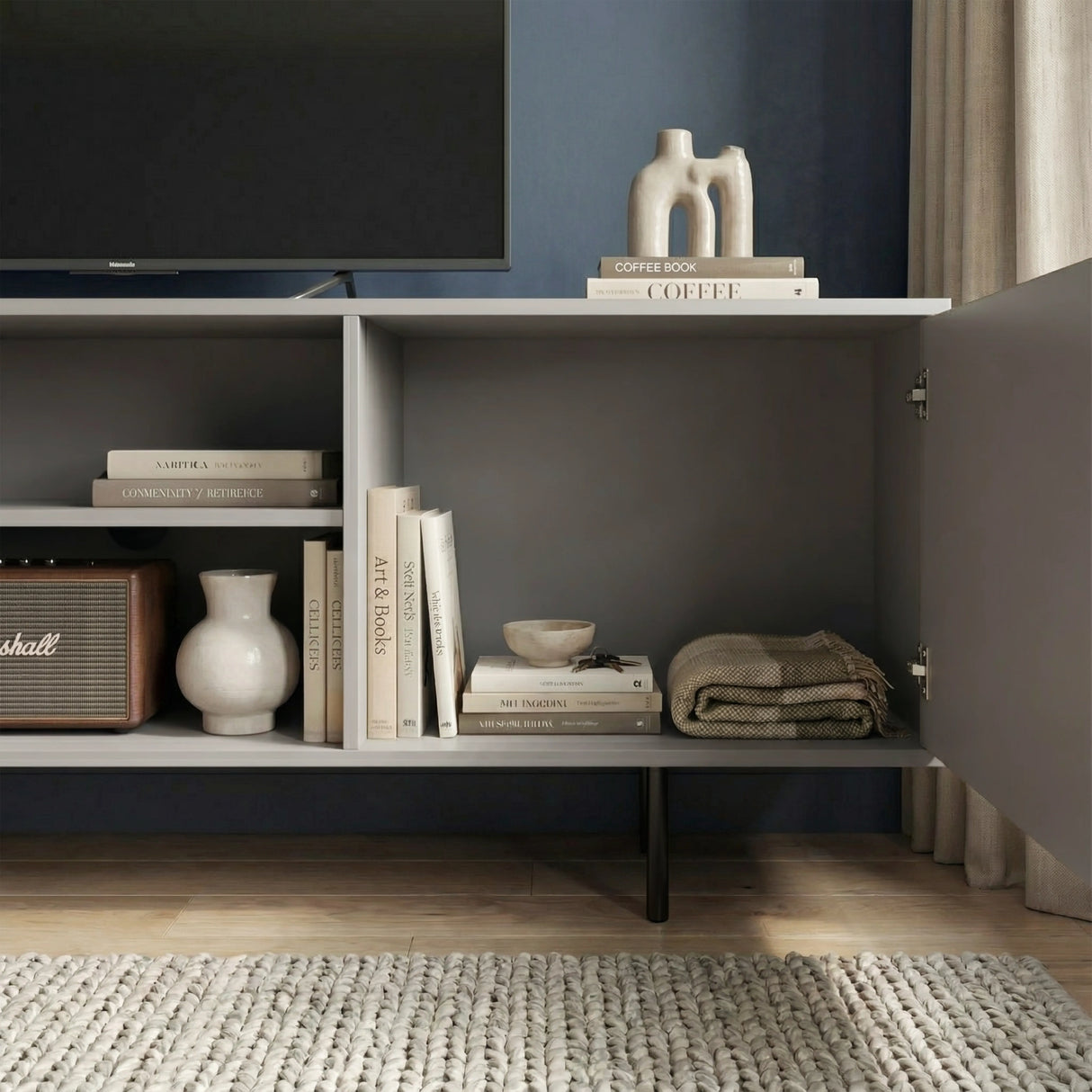 Grey TV storage unit showing internal shelves and fluted doors, designed for organized media and home accessories.