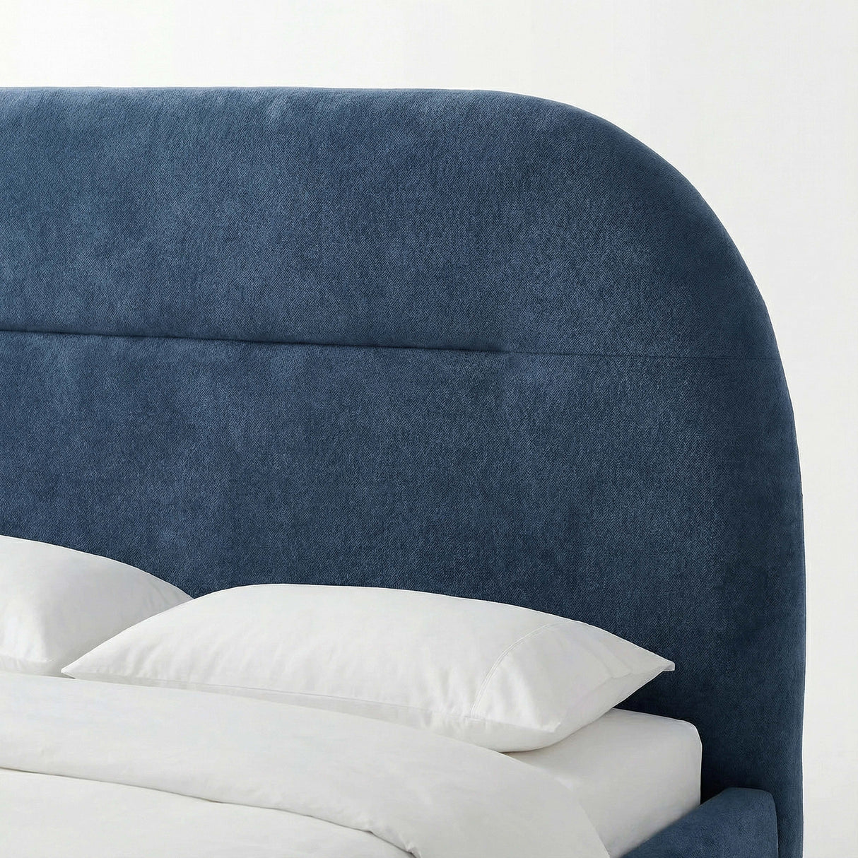 Close-up view of the padded headboard on the blue upholstered bed frame with white bedding